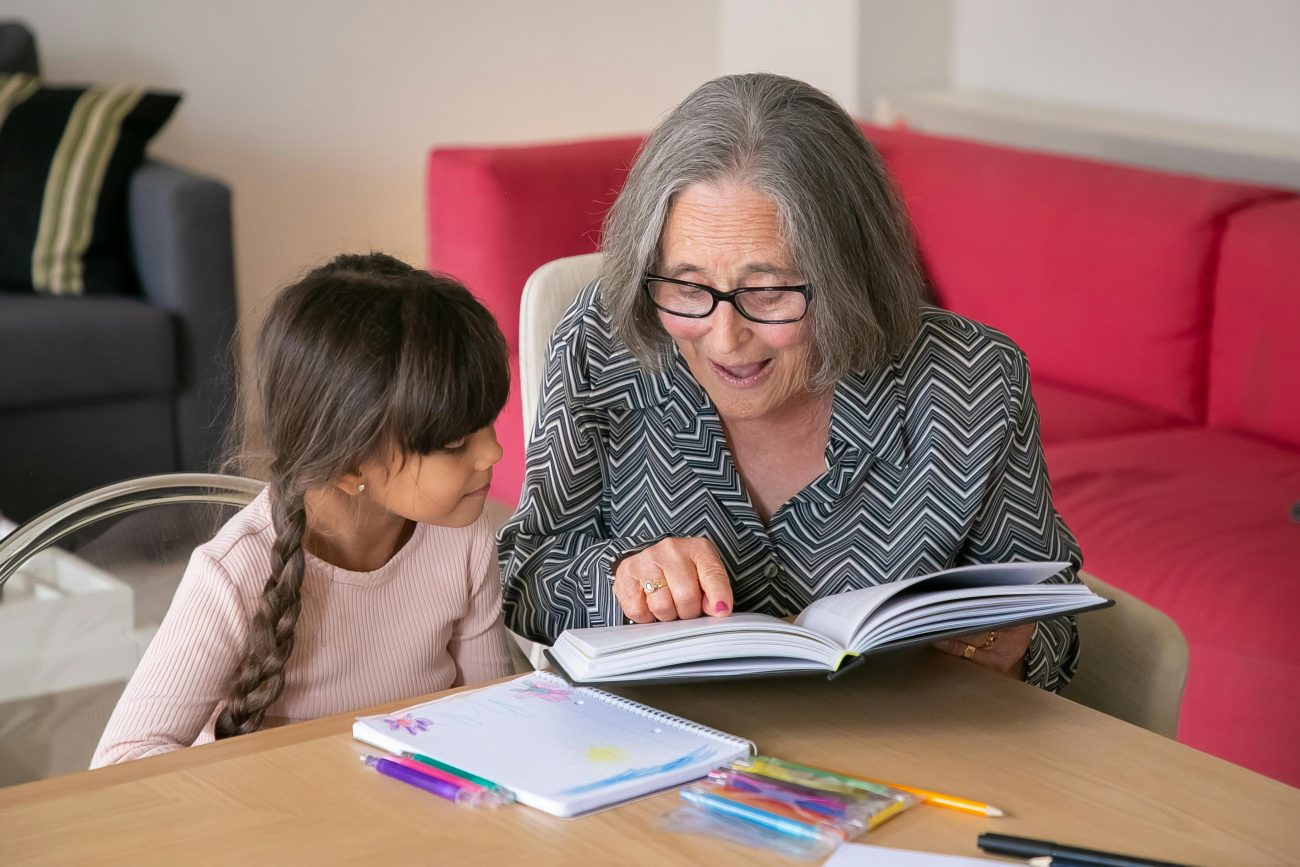 An older lady offering 1-2-1 tuition to a pupil.