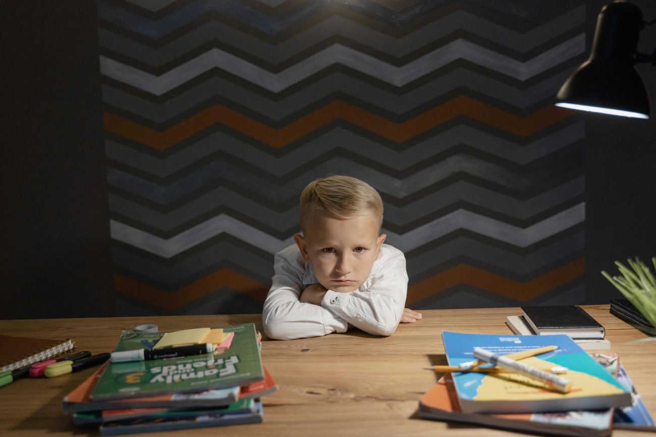 A young blonde boy is struggling with school work.